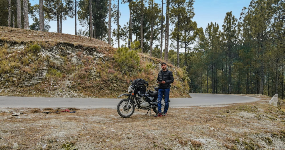 a man standing next to a motorcycle on a dirt road