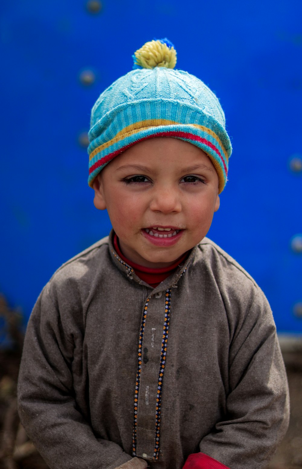 a young boy wearing a blue and yellow hat