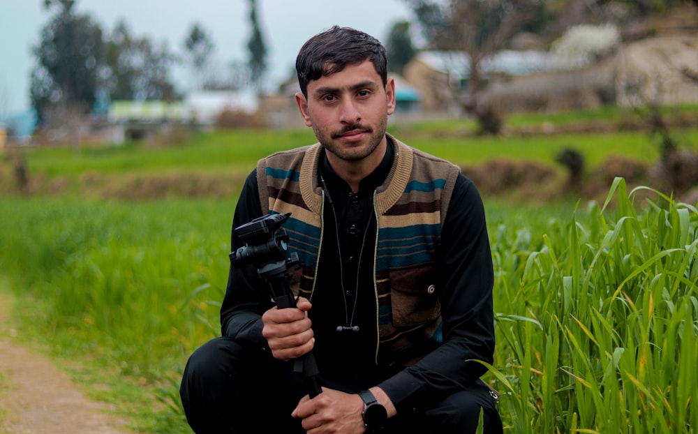 a man sitting in a field holding a camera