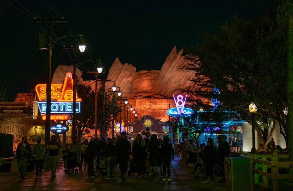 a crowd of people walking down a street at night