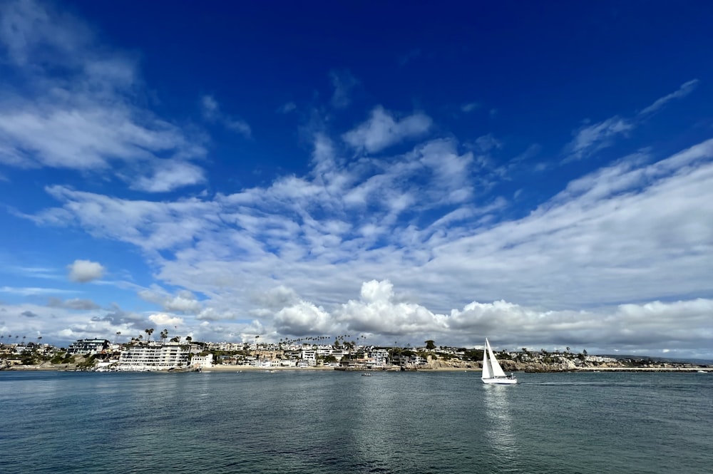 a sailboat on the water with a city in the background