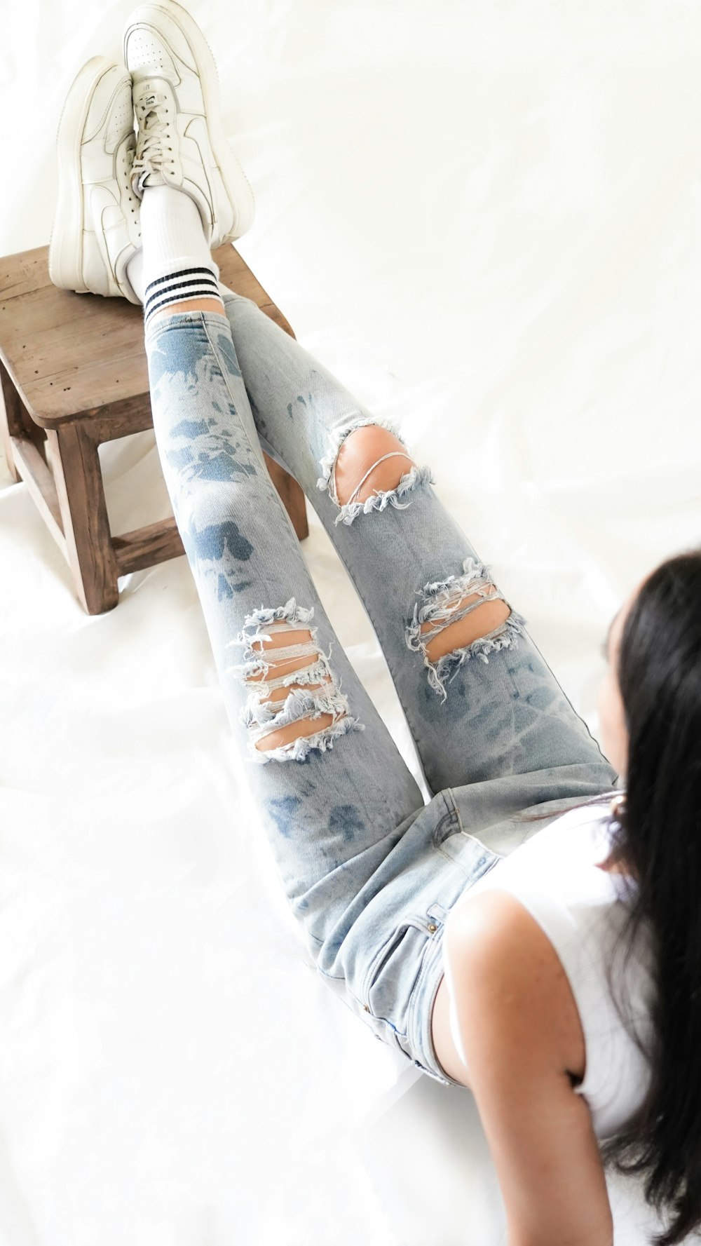 A woman laying on top of a bed wearing ripped jeans photo – Free Jeans  Image on Unsplash