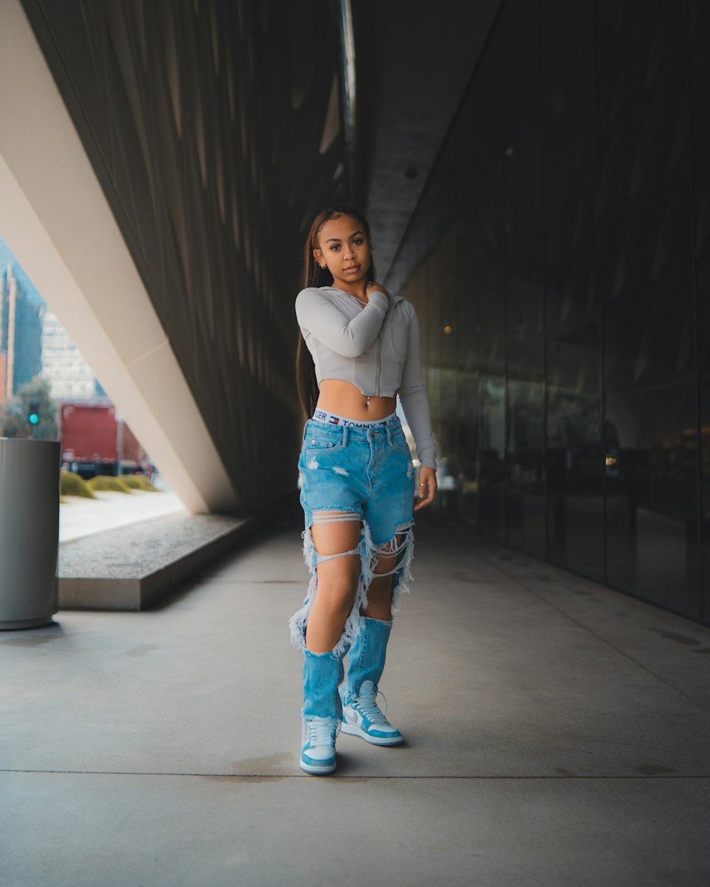 a woman in ripped jeans and boots walking down a sidewalk