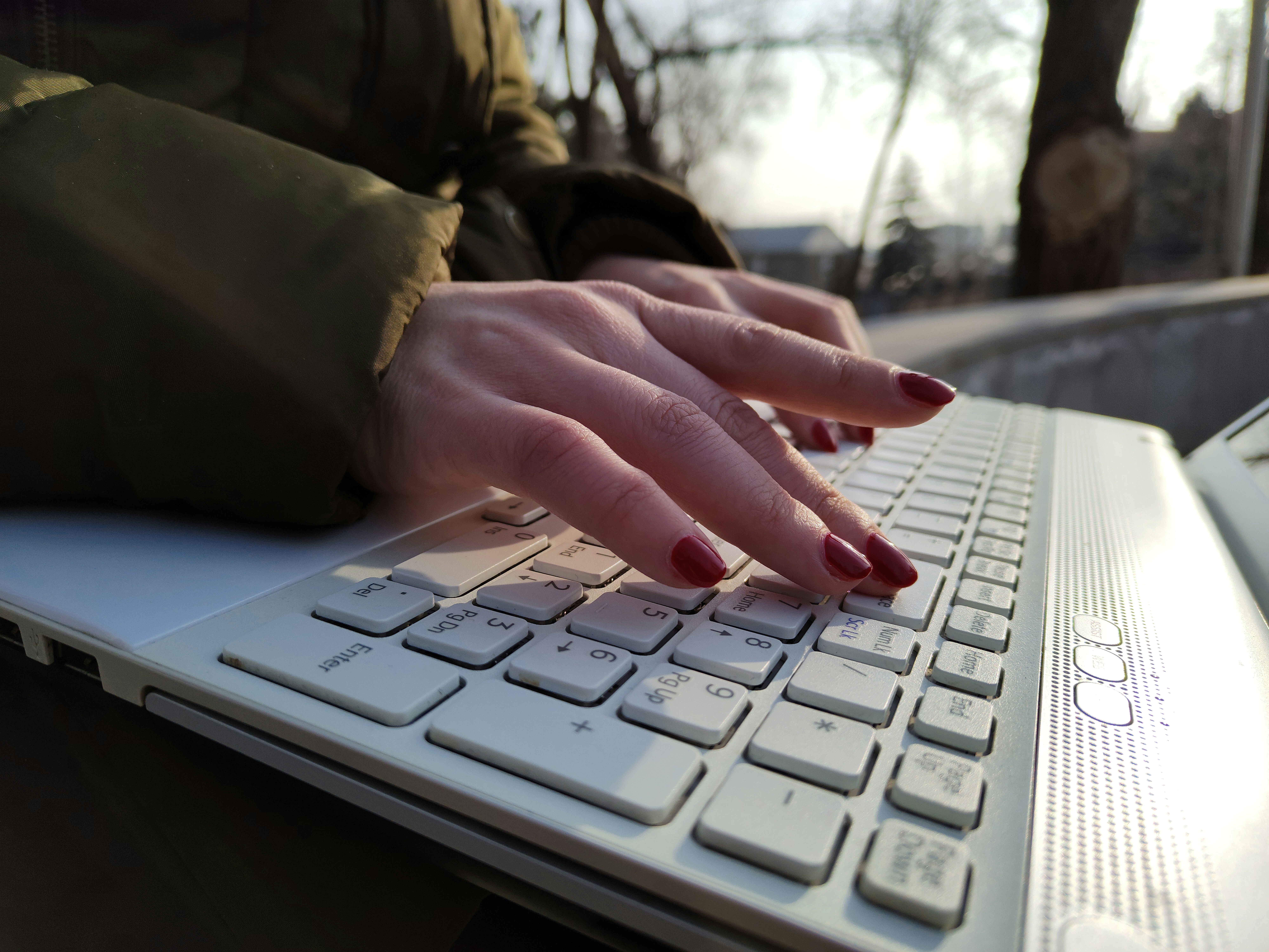 a mão de uma mulher está no teclado de um laptop