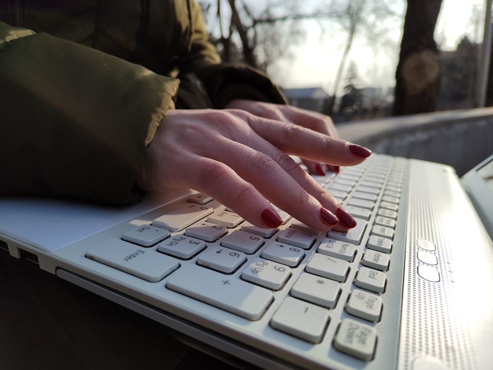 a mão de uma mulher está no teclado de um laptop