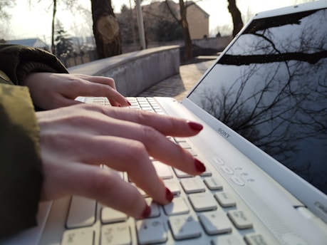 a person typing on a white laptop computer