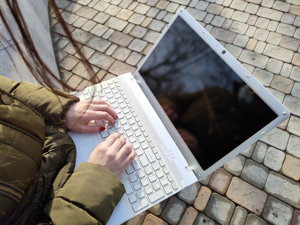 a woman is typing on a laptop outside