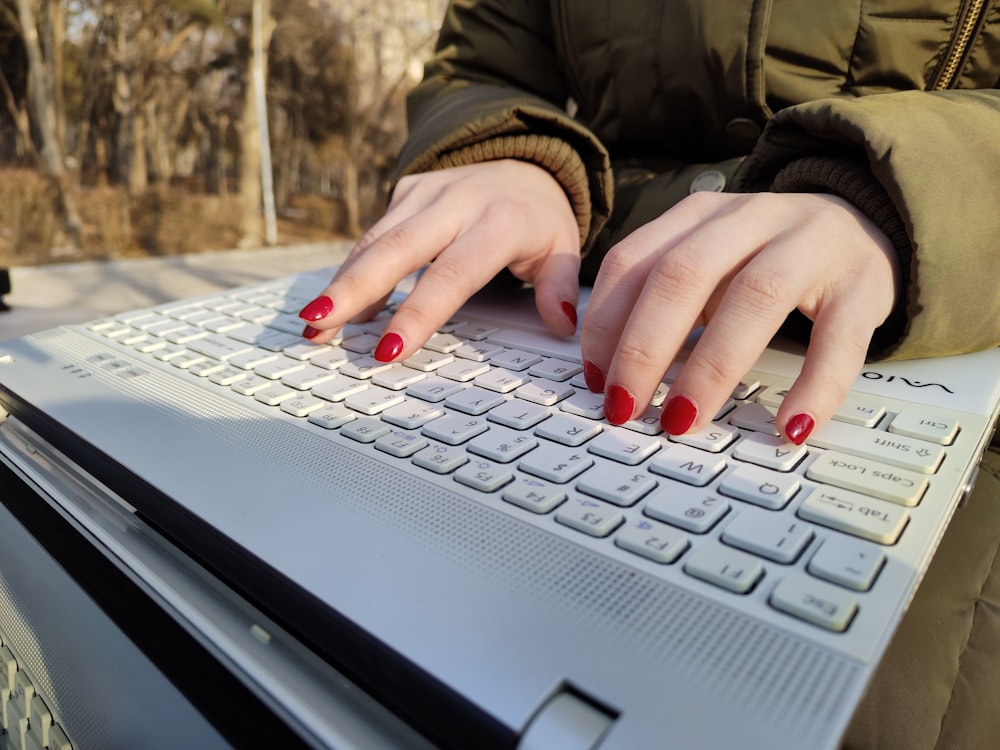 a woman's hands on top of a laptop keyboard