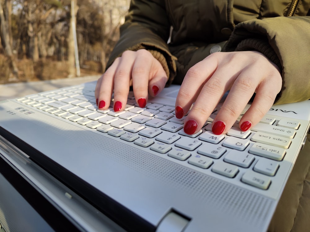 a woman with red nails typing on a laptop