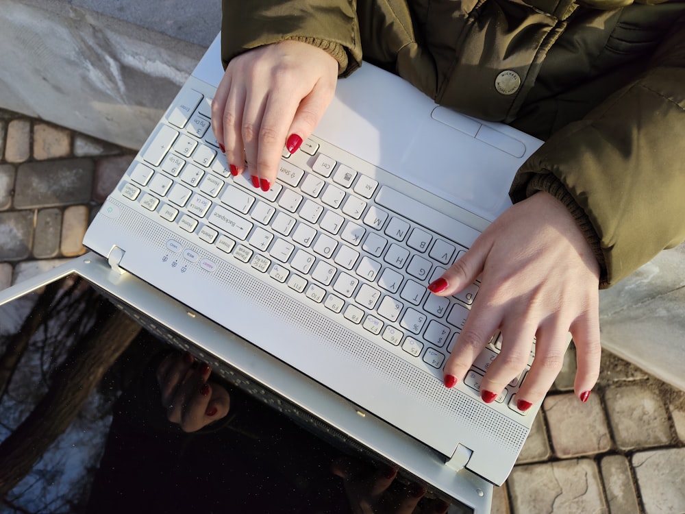 a woman is typing on a laptop outside