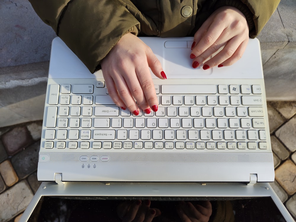 a woman is typing on a white keyboard