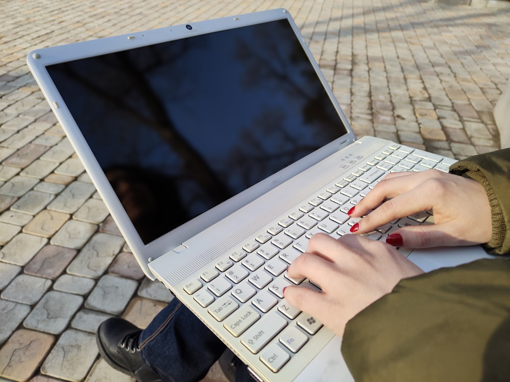 a woman is typing on her laptop outside
