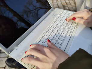 a woman is typing on a laptop outside