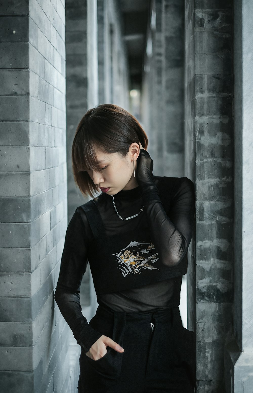 a woman leaning against a wall with her hand on her head