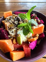a purple bowl filled with assorted fruits and nuts