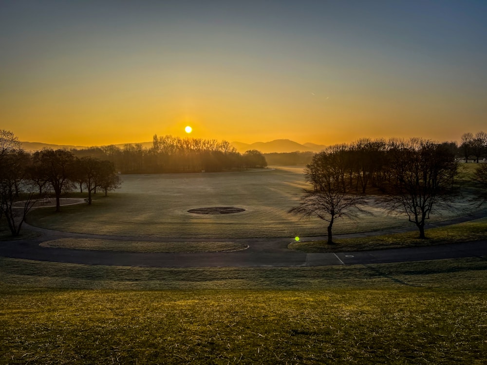 the sun is setting over a golf course