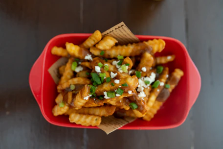 Golden fries served in a red container with a side of tangy dipping sauce.