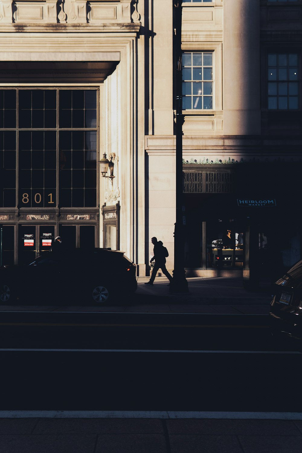 a man walking down a street next to a tall building