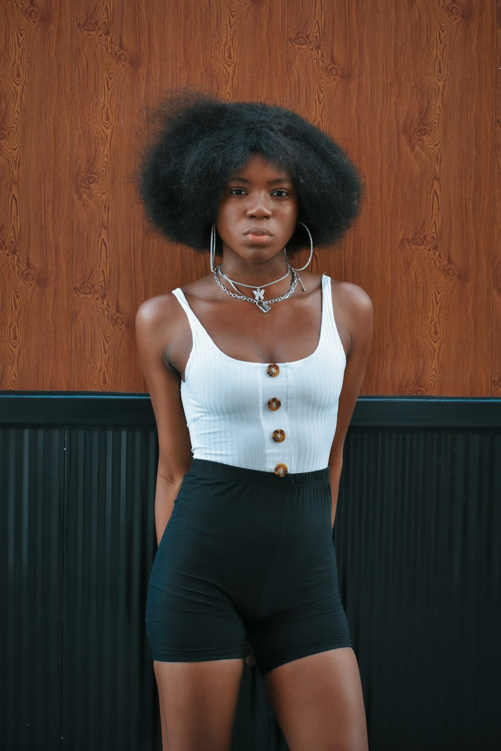 a woman with an afro standing in front of a wooden wall