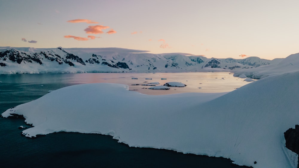 a large body of water surrounded by snow covered mountains