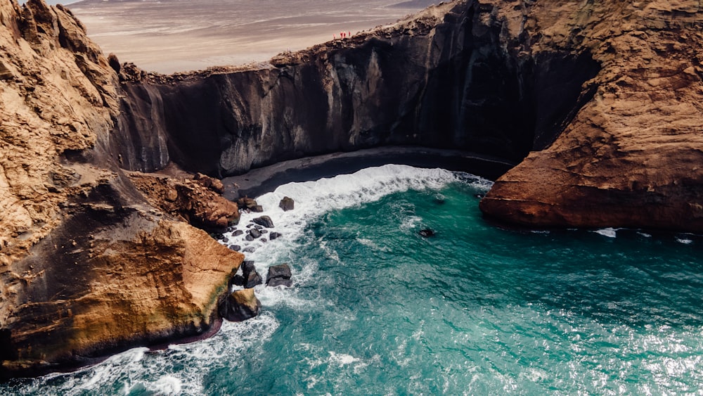 an aerial view of a body of water near a rocky cliff