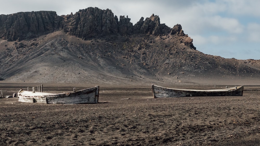 a couple of boats sitting on top of a dirt field