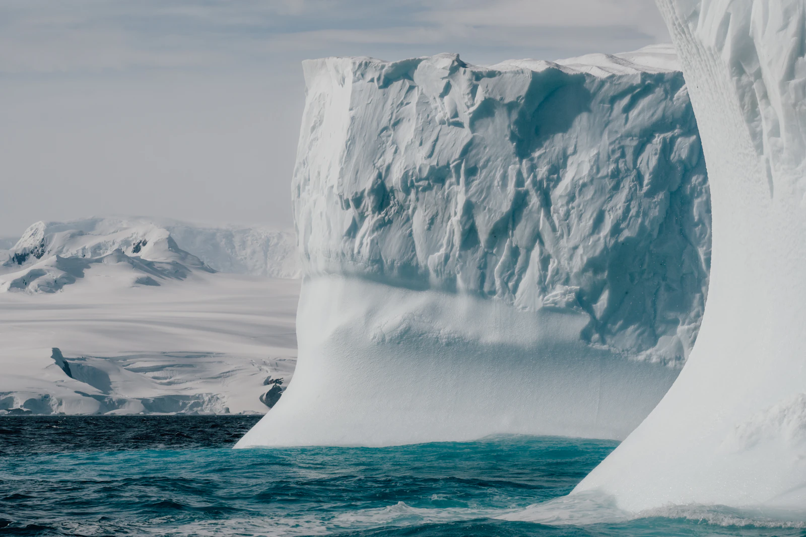 A vast iceberg floating in still polar ocean under pale light