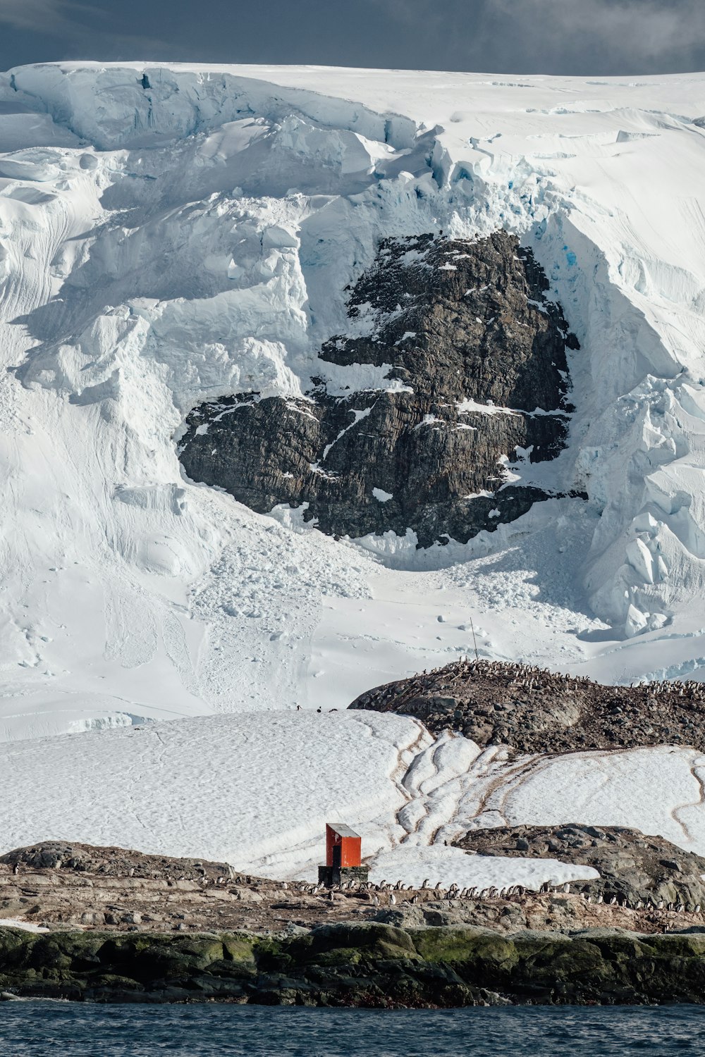 a large mountain covered in snow next to a body of water