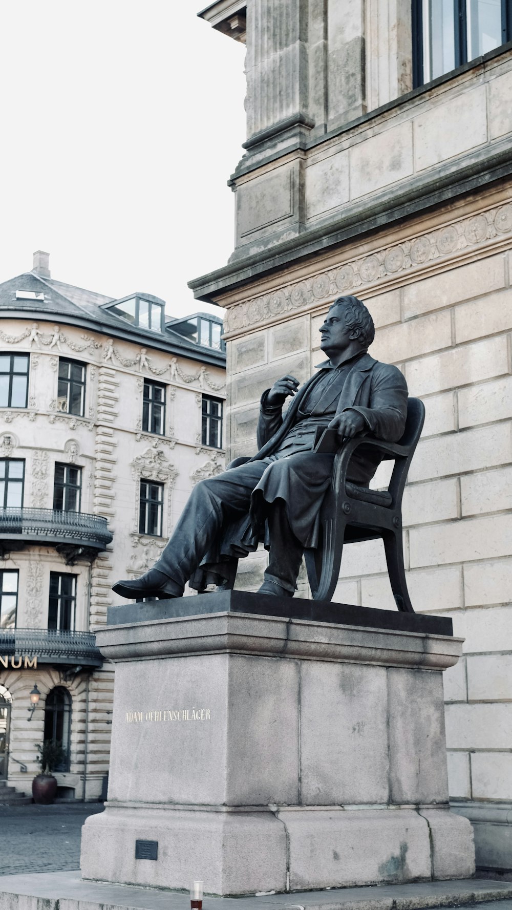 a statue of a man sitting on a bench in front of a building