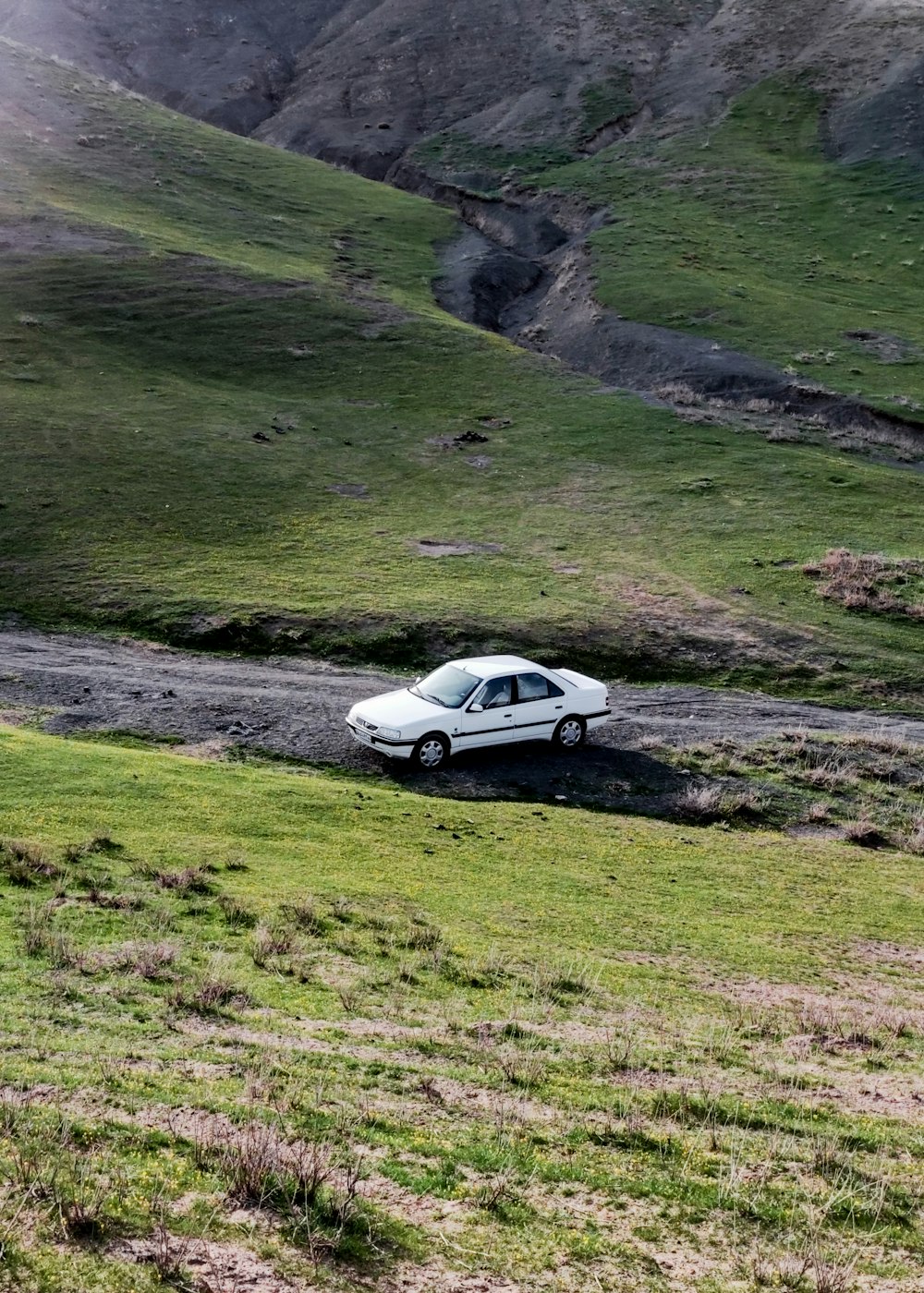 a small white car parked on a dirt road