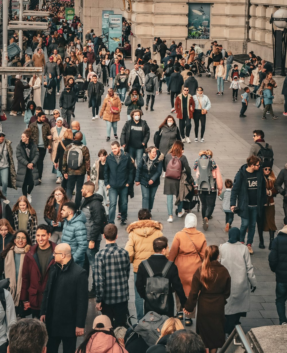 a crowd of people walking down a street next to tall buildings