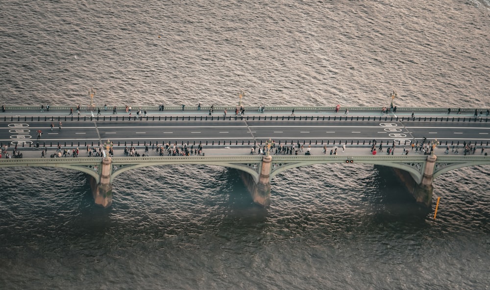 a group of people walking across a bridge over water