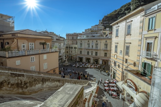 A bustling town square with neighbors chatting and local shops in the background on a sunny day.