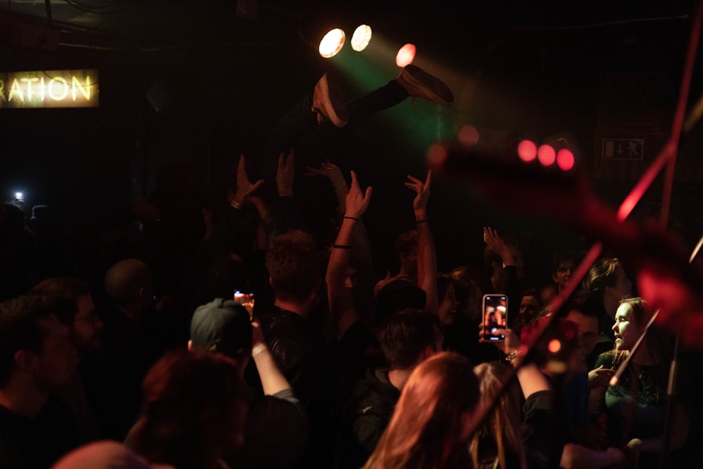 a crowd of people at a concert with their hands in the air