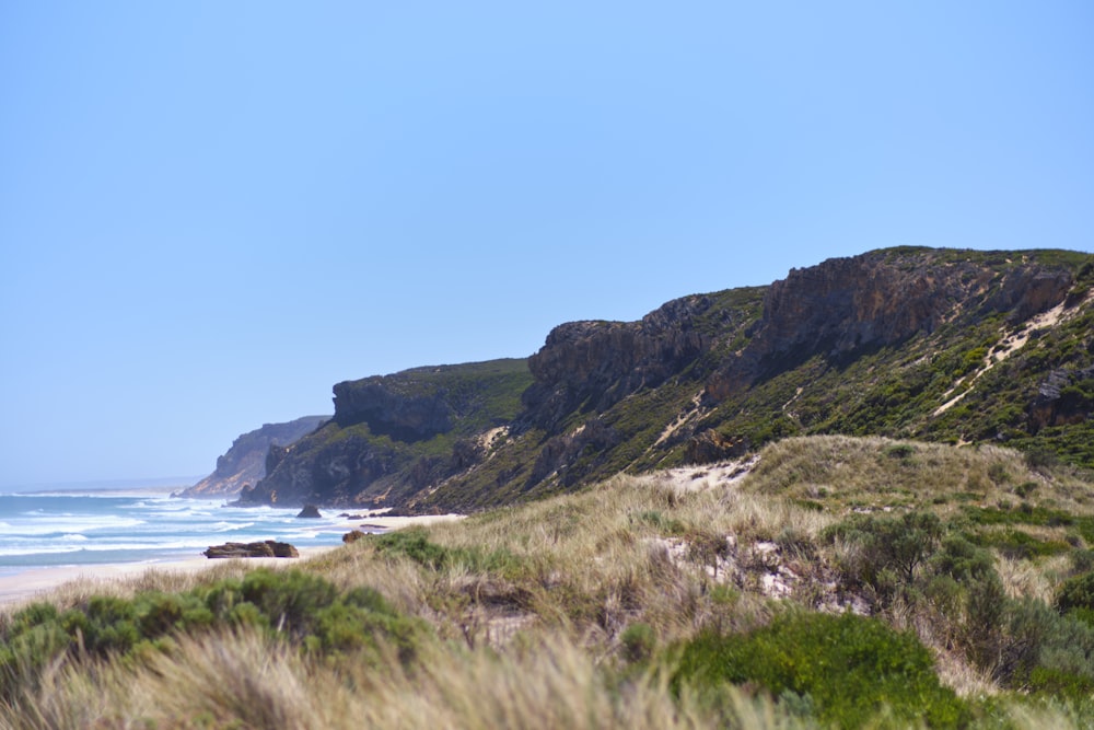 a sandy beach next to the ocean with a mountain in the background