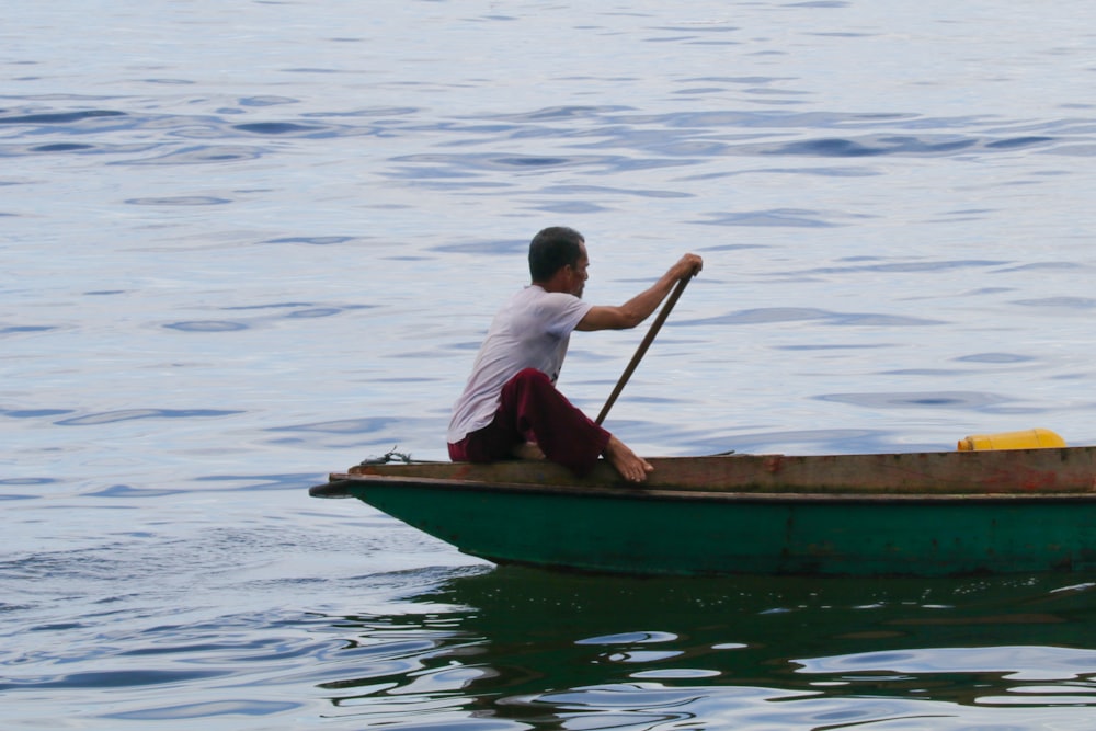 a man sitting in a green boat on the water