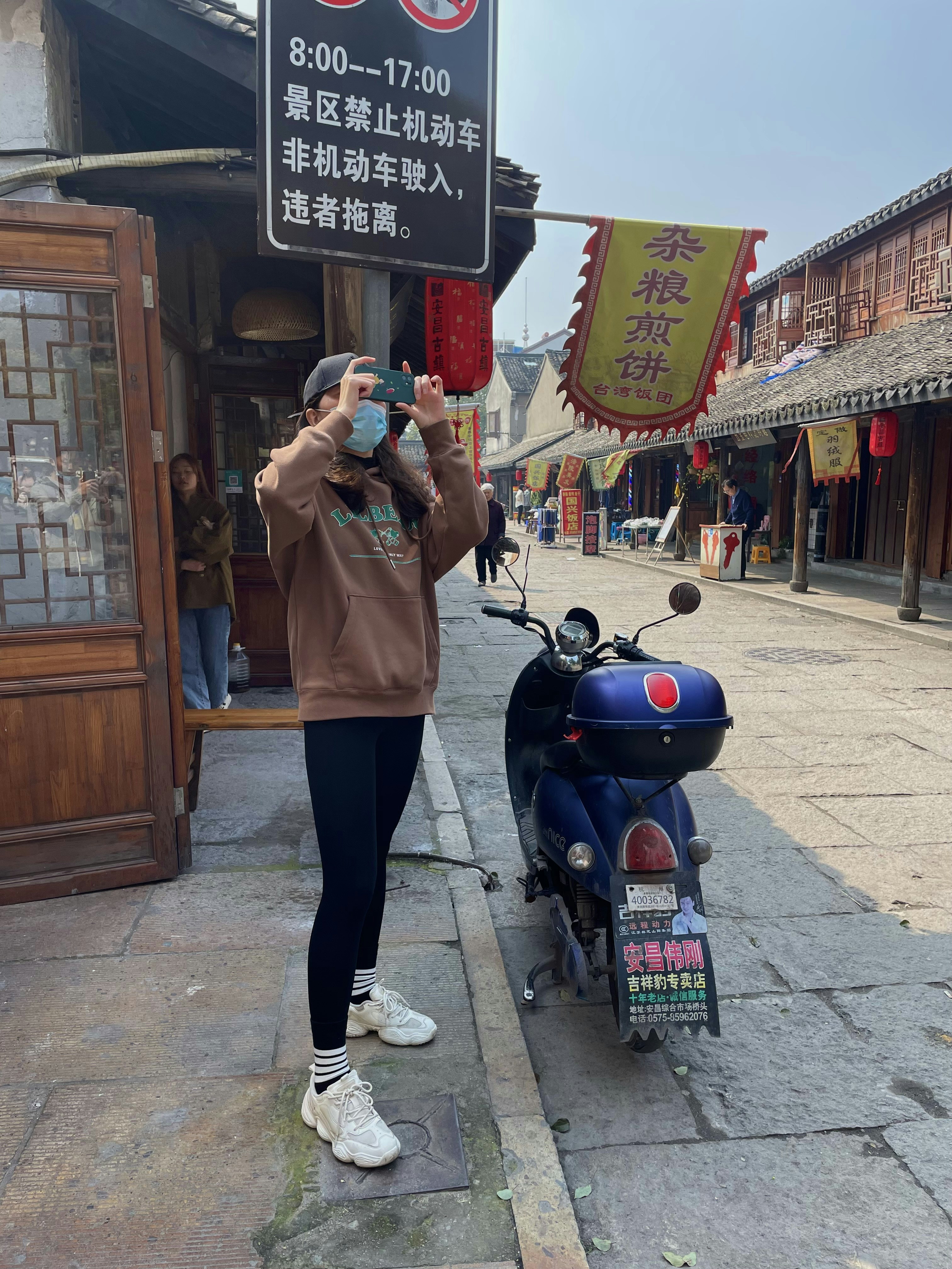 a woman taking a picture of a man on a scooter