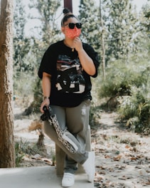 a woman in a black shirt is holding a skateboard