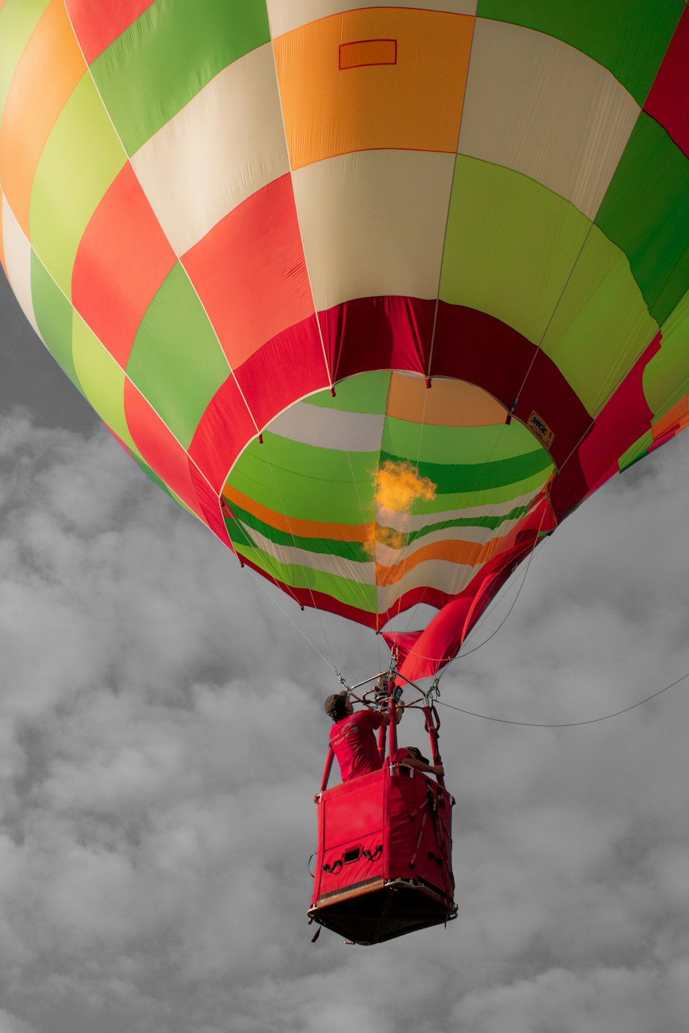 a large colorful hot air balloon flying through a cloudy sky