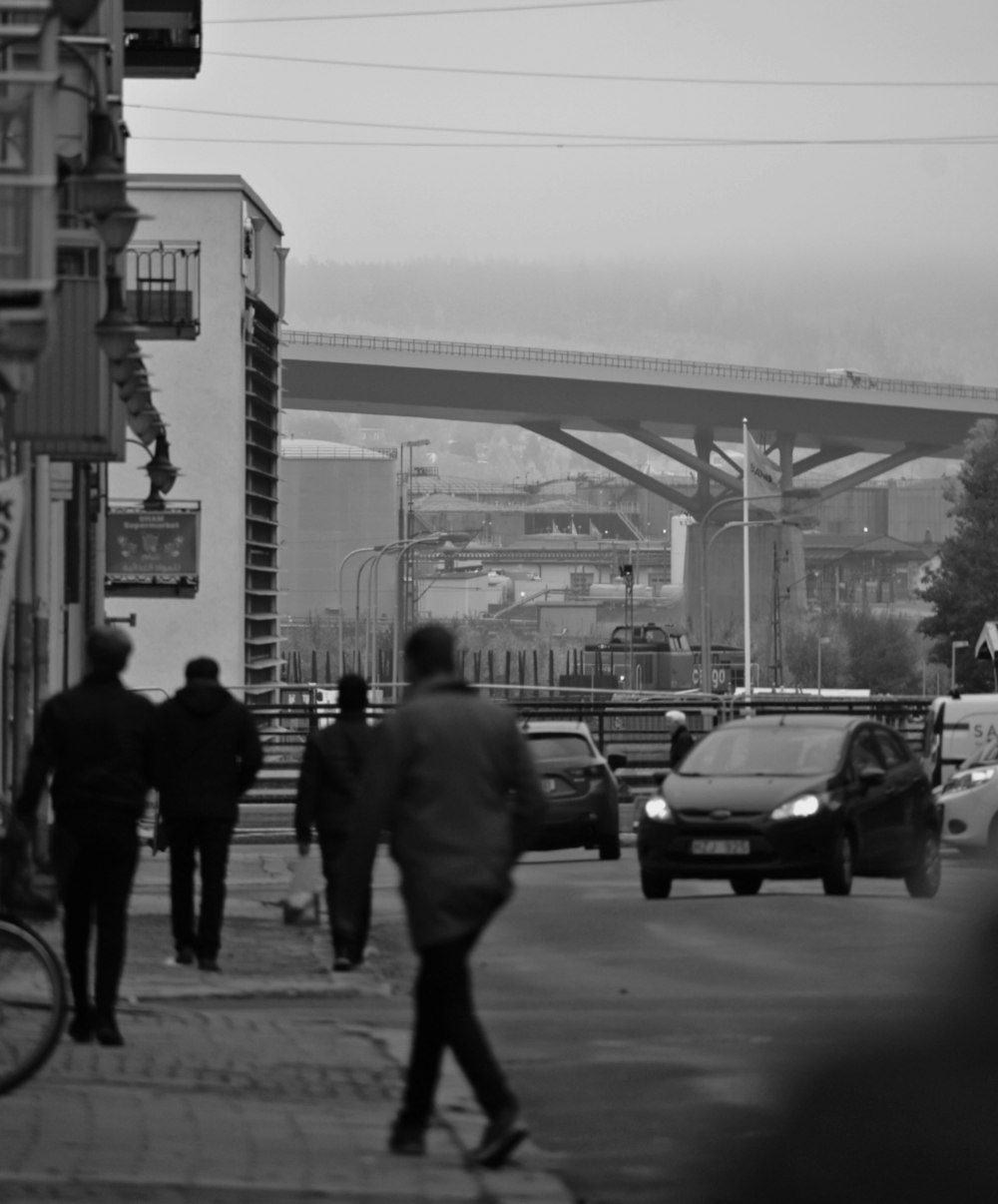 a group of people walking down a street next to a bridge