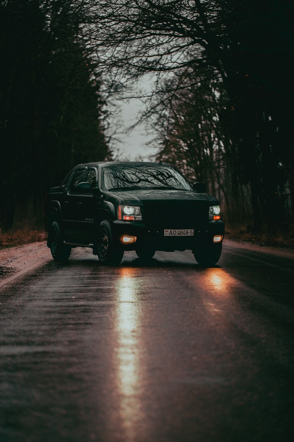 a black truck driving down a wet road
