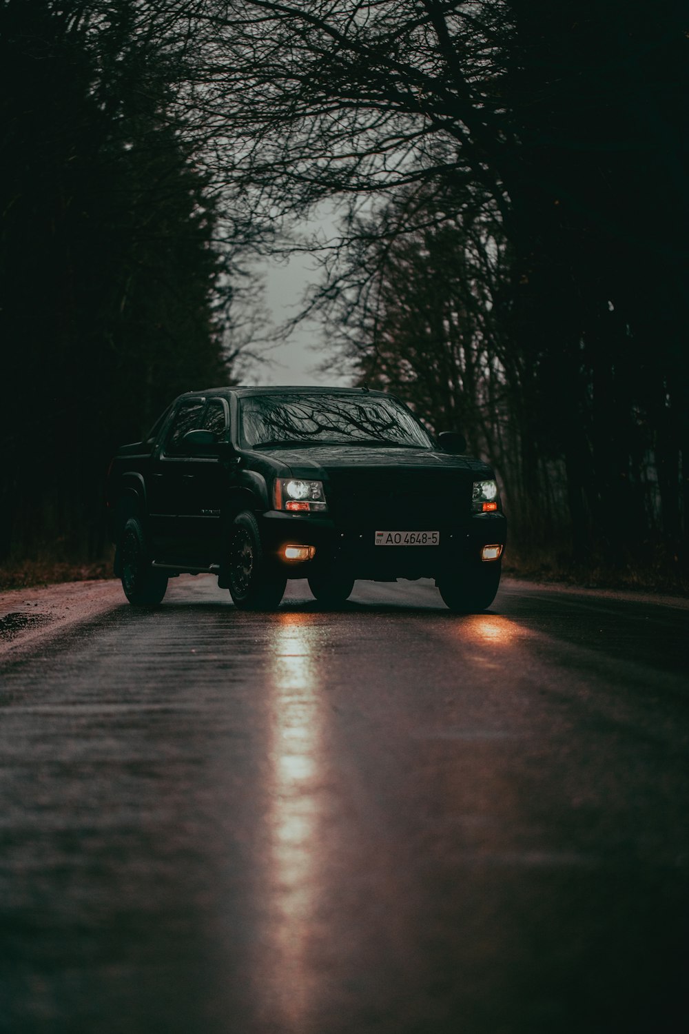 um caminhão preto dirigindo por uma estrada molhada
