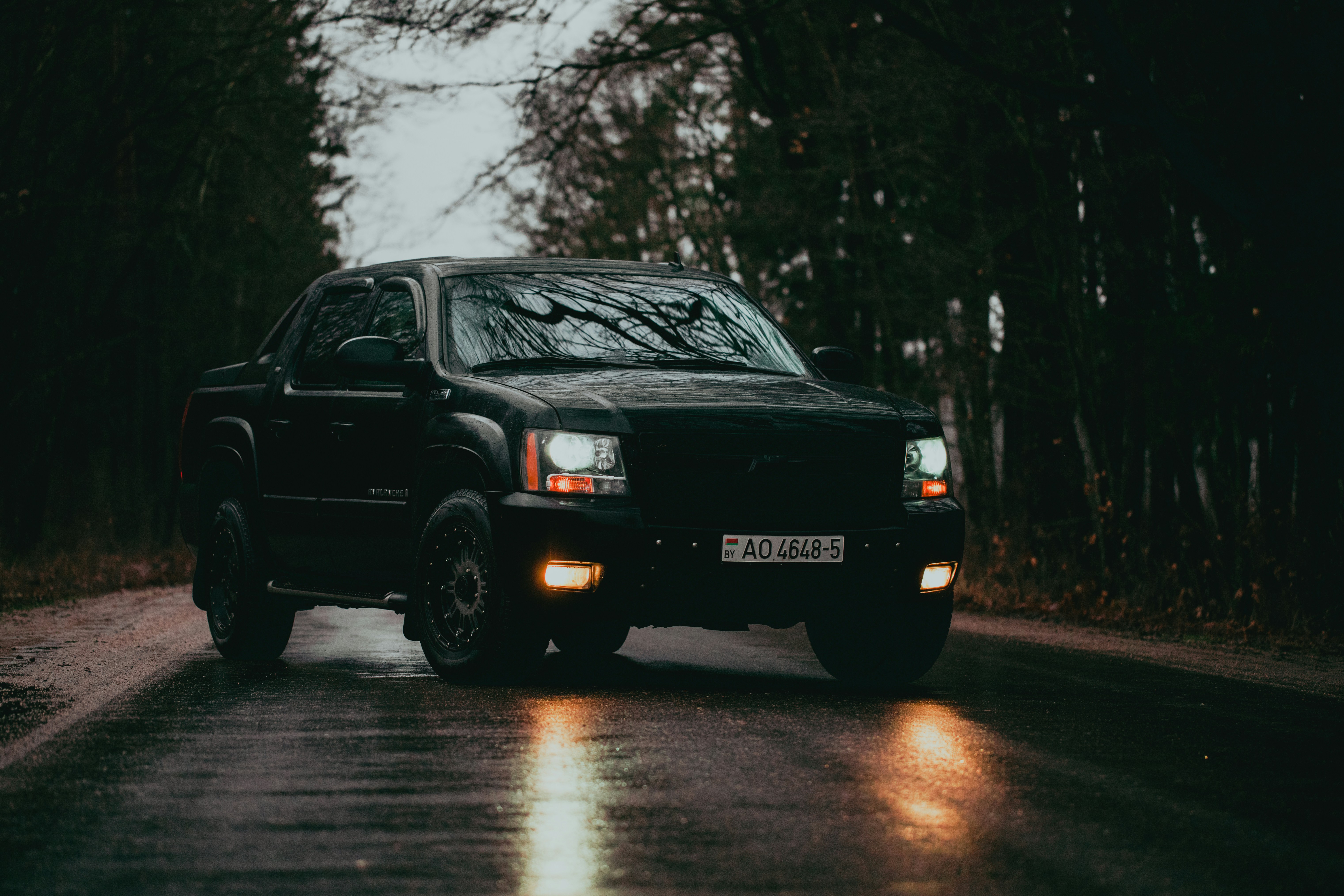 a black truck driving down a wet road