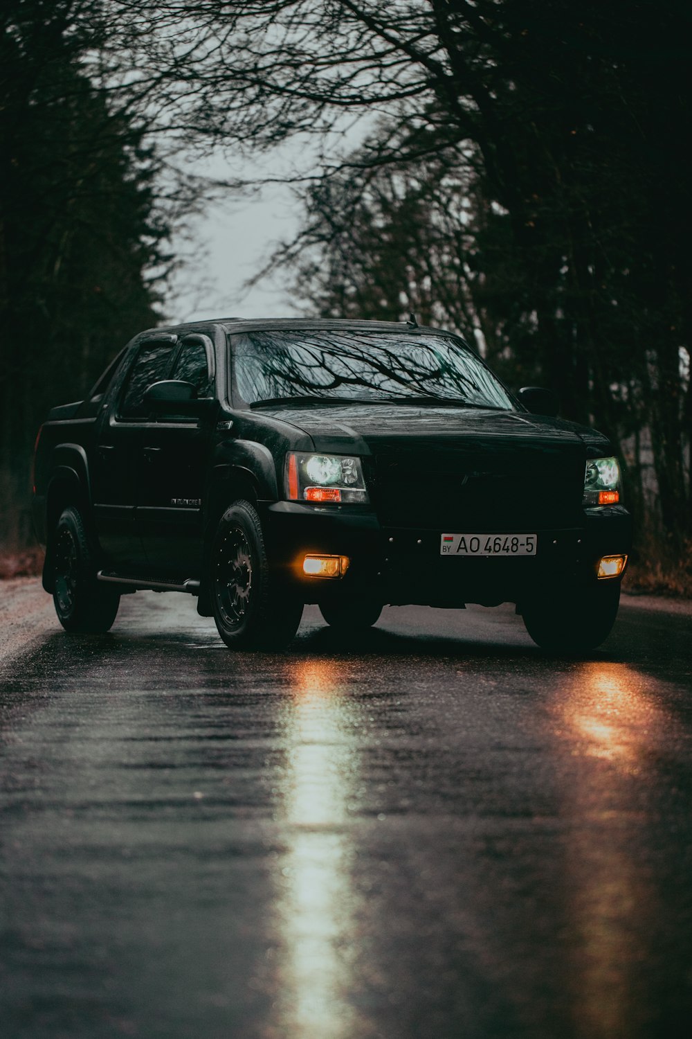 a black truck driving down a wet road