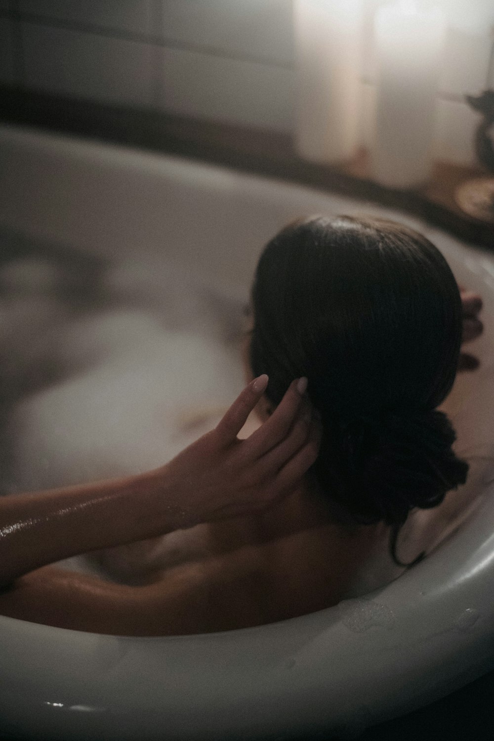 a woman sitting in a bathtub with her hands on her head