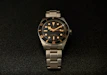 a watch sitting on a black surface with gold numbers
