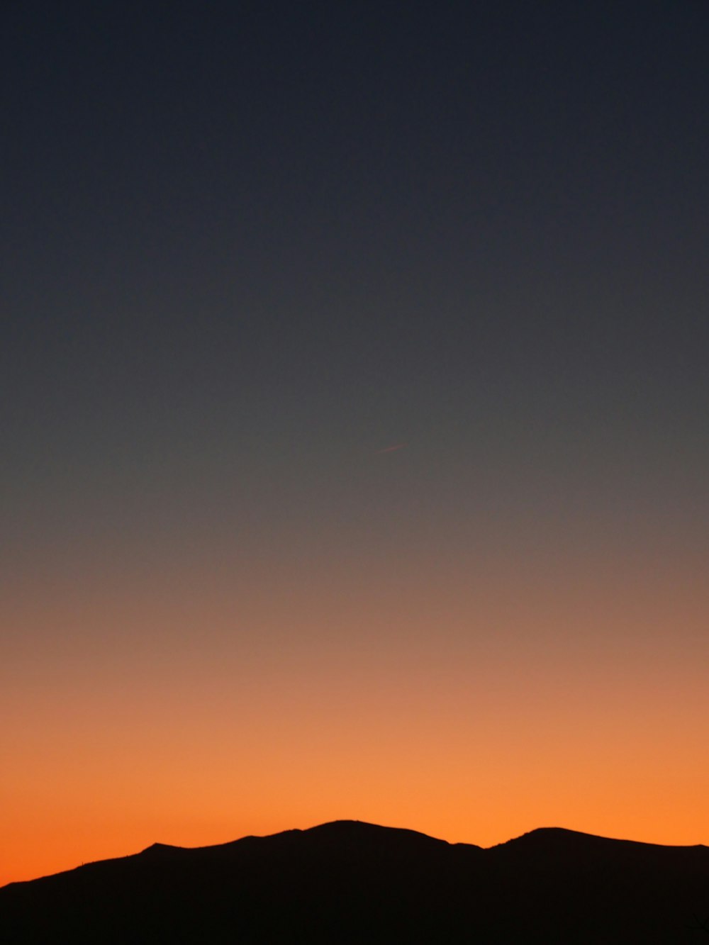 a plane flying in the sky at sunset