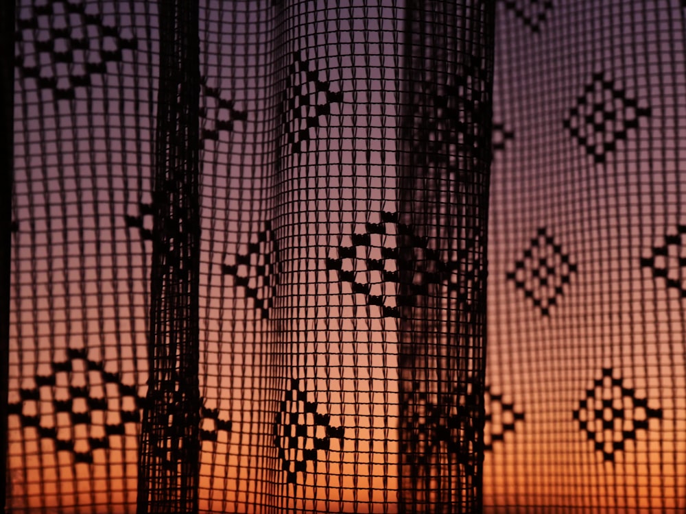a close up of a curtain with a sunset in the background