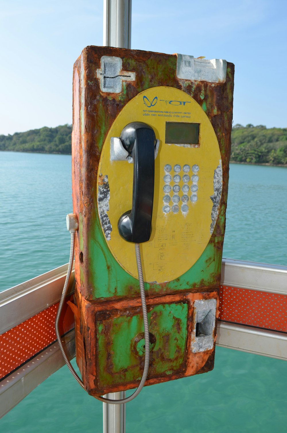 an old phone is sitting on a pole near the water