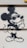 A graffiti-style drawing on a wall depicts a well-known cartoon mouse character wearing sunglasses and giving a cheeky expression with one hand gesturing. The artwork uses bold black outlines on a light-colored surface.